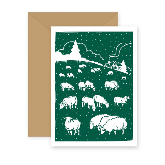 Sheep in the Snow letterpress greeting card with kraft envelope — a flock of sheep grazing in falling snow below a farmhouse